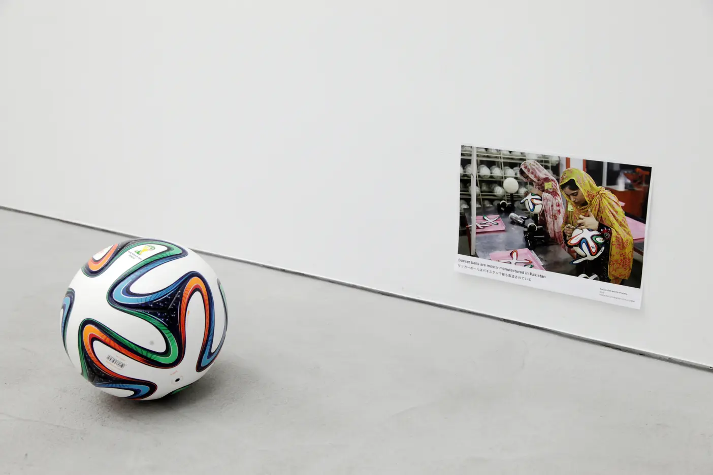 “Soccer ball and Its Process”. Soccer ball, photograph print on paper. 2018. Text: “Soccer balls are mostly manufactured in Pakistan”