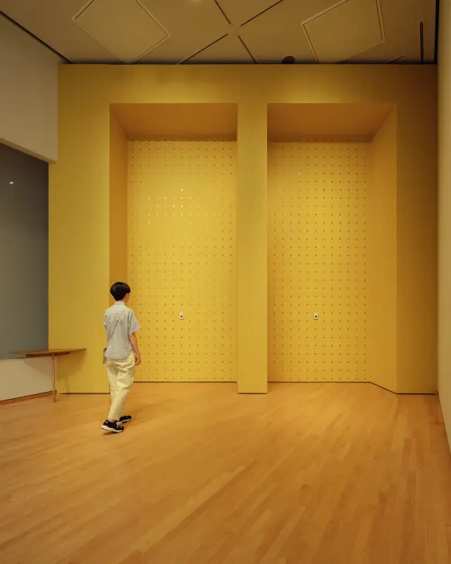 We are talking through the yellow wall ・ 2023 Tokyo ・ Wood, wallpaper, table, door chime, Braille sticker, acrylic resin, transgender Flag, bookshelf, handwriting, Wall section: 520 cm high, 1230 cm wide, Wallpaper provided by Sangetsu Co., Supported by: Printos Co., photo: Hideki Ookura